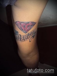 Фото тату рубина с надписью 'Ruby' на руке. Простой, но эффектный рисунок татуировки с красным камнем и черными контурами.