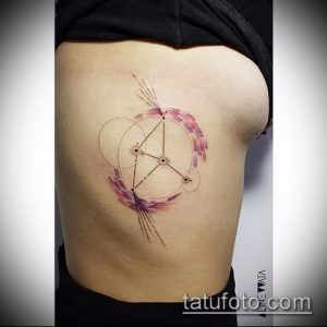 Фото акварельной татуировки созвездия на женском боку. Нежные розовые и фиолетовые оттенки создают эффект размытости. Красивый и оригинальный рисунок татуировки.