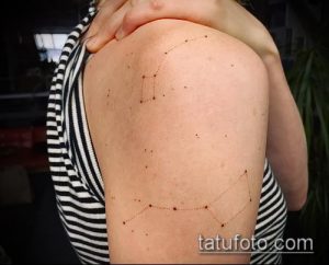 Фото тату созвездия на плече девушки. Тонкие линии соединяют точки, образуя рисунок созвездия на загорелой коже. Минималистичный дизайн.