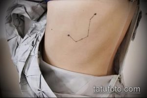 Фото минималистичного тату созвездия на боку. Рисунок выполнен тонкими линиями и выглядит очень нежно и изящно.