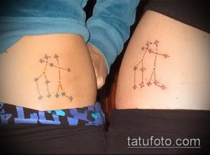 Фото парных тату созвездий на бедрах двух девушек. Рисунки выполнены в разных цветовых гаммах: голубой и оранжевый, что придает им индивидуальность.