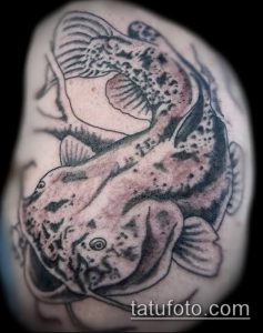 Фото татуировки сома в стиле blackwork на плече. Монохромный рисунок с использованием плотной штриховки и геометрических элементов. Стильный и минималистичный эскиз.