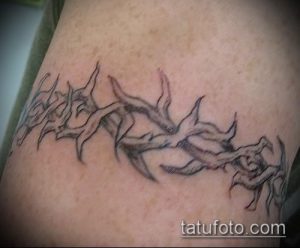 Фото татуировки: колючая проволока, выполненная в стиле blackwork на руке. Черно-белый рисунок татуировки с использованием плотных черных линий.
