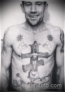 Фото тату распятия и религиозных символов на груди, выполненное в черно-белых тонах с использованием традиционной техники.