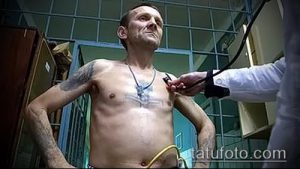 Фото тату креста и религиозных символов на груди, выполненное в черно-серых тонах с детальной проработкой.