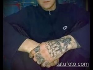 Фото тату полностью покрытой рисунками и надписями руки, характерной для тюремной татуировки, выполненной в черно-серых тонах.