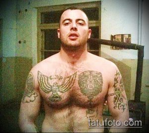 Фотография мужчины с татуировками на груди и плечах, изображающими орла и волка. Детализированный рисунок в реалистичном стиле.