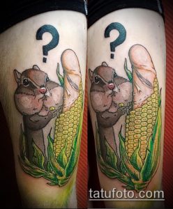 Фото татуировки с изображением белки, держащей кукурузу и стоящей под знаком вопроса, выполненной в ярком и мультяшном стиле.
