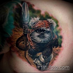 Фото тату Ewok из Звездных войн на плече. Реалистичный рисунок с проработкой шерсти и деталей костюма. Яркие цвета и детализированный фон.