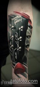Фото тату гитары Gibson на руке. Детализированный рисунок с логотипом и элементами гитары. Черно-красная цветовая гамма.