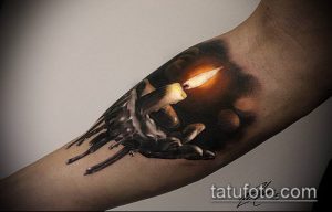 Фото реалистичной татуировки горящей свечи на руке, выполненной с использованием желтых, оранжевых и черных оттенков. Изображение свечи с капающим воском и ярким пламенем.