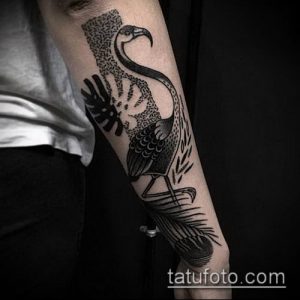 Фото тату фламинго, выполненного в технике blackwork на мужской руке. Контрастный и стильный рисунок с использованием черных чернил.