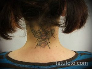 Фото небольшой татуировки шмеля на затылке. Минималистичный рисунок татуировки с четкими контурами и детализацией.