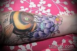 Цветная татуировка шмеля, сидящего на цветке, выполненная в ярких и насыщенных цветах.