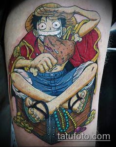 Фото тату Луффи из One Piece, сидящего в сундуке с сокровищами, на руке. Яркие цвета, детализированная проработка и динамичная композиция.