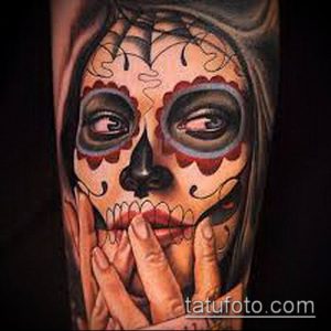 Фото тату на руке с изображением женского черепа в стиле Sugar Skull, украшенного цветами и узорами. Яркий и детализированный рисунок татуировки.