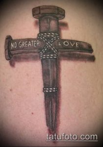 Фото тату гвоздя, символизирующего крест, с надписью 'No Greater Love'. Мрачный и символичный рисунок татуировки, выполненный в черно-серых тонах.