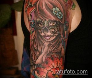 Фото тату на плече: татуировка в стиле Day of the Dead с изображением девушки-черепа, украшенной цветами, яркие цвета и детализированный рисунок.