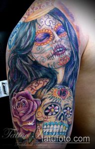 Фото тату на плече: яркая татуировка в стиле Day of the Dead с изображением девушки-черепа и роз, красочная и детализированная.