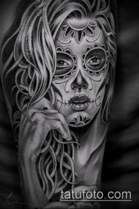 Фото татуировки в стиле Sugar Skull на руке. Изображение женского черепа с длинными волосами и детальным макияжем, выполненное в черно-белой гамме.