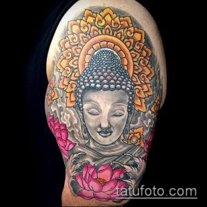 Яркая татуировка на плече с изображением Будды, окруженного золотым нимбом, цветами лотоса и розовыми цветами.