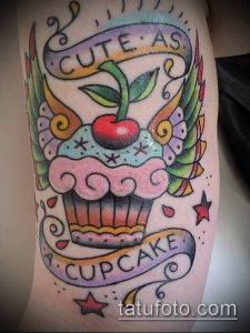 Классическая татуировка капкейка в стиле олдскул с надписью "Cute as a cupcake" и яркими крыльями. Идеально для любителей винтажных рисунков.