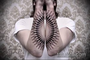 Фото тату на предплечьях, изображающих симметричные крылья. Черно-белая татуировка с добавлением красных акцентов, выполненная в графическом стиле.
