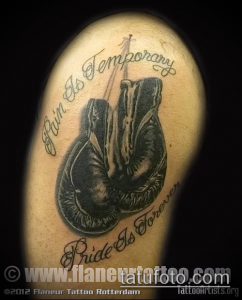 Фото тату: боксерские перчатки с цитатой 'Pain Is Temporary, Pride Is Forever' на руке, черно-серые тона, реалистичный рисунок.