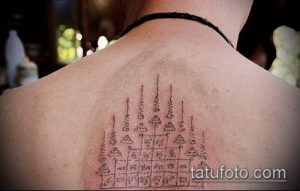 Фото тату на спине, изображающее геометрический узор Янт. Черно-серая татуировка с четкими линиями и сложной структурой.