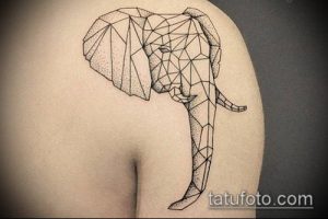 Фото татуировки на плече, изображающей слона, стилизованного под геометрические фигуры. Слон выполнен в черном цвете с точечной штриховкой.