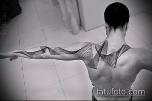 Фото тату с абстрактным рисунком из волнообразных черных линий. Минималистичный дизайн татуировки, расположенный на плече и верхней части спины мужчины.