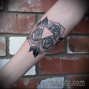 Черно-белое фото тату с изображением роз и треугольника на руке, выполненное в графическом стиле.