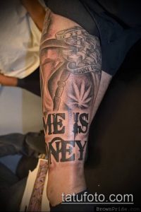 Фото тату: изображение лица с маской, символами свободы и надписью "ME IS KEY", выполненное в черно-серых тонах на руке.