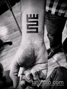 Фото минималистичной татуировки на запястье с надписью 'LOVE', выполненной в геометрическом стиле. Простой и лаконичный рисунок татуировки.