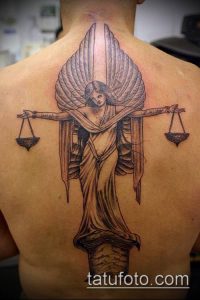 Фото тату богини Фемиды с весами и повязкой на глазах на спине. Детализированный черно-белый рисунок татуировки.