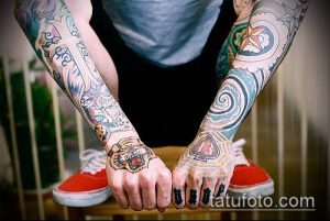 Фото тату, покрывающих обе руки. Разноцветные рисунки в стиле олдскул и традиционные мотивы. Яркие цвета и детализированные изображения.