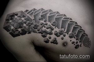 Фото тату: Черно-белая татуировка с геометрическим рисунком, изображающим разрушающиеся кубы на мужской груди. Детализированный рисунок татуировки.