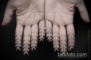 Фотография татуировок на ладонях, изображающих стилизованные перья, выполненные в технике дотворк. Перья расположены вдоль пальцев.