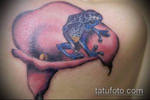 Фото тату лягушки на цветке. Яркий рисунок с использованием синих, желтых и красных оттенков. Идеальный эскиз для татуировки на плече.