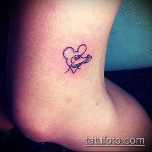 Маленькая татуировка на лодыжке, изображающая голову Микки Мауса внутри сердца. Черно-белый рисунок татуировки в милом и нежном стиле.