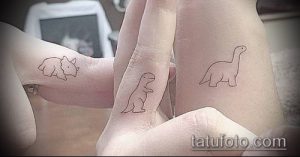 Фотография парных татуировок на пальцах: на одном пальце изображен трицератопс, на другом – брахиозавр. Черно-белое изображение, минималистичный стиль.