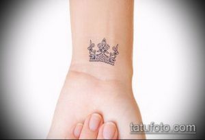 Фото изящной татуировки короны, выполненной тонкими линиями на запястье девушки.
