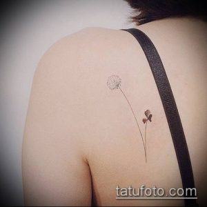 Фотография минималистичной татуировки одуванчика на женской спине. Изящный рисунок с тонкими линиями и рассеянными семенами.