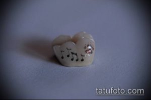 Фото тату на зубе: ноты и небольшие цветы, выполненные в черном и красном цветах. Оригинальный дизайн для меломанов.
