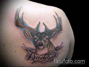 Фото тату оленя с надписью "Daddy" на ленте. Рисунок выполнен в ярких цветах с использованием теней.