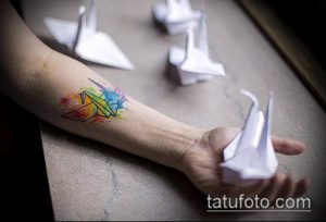 Фото тату оригами птицы в акварельной технике на руке, с использованием ярких и насыщенных цветов. Креативный и оригинальный рисунок татуировки.