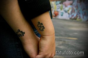 Фото парных татуировок пазлов на запястьях. Черные контурные рисунки, символизирующие единство и взаимодополнение.
