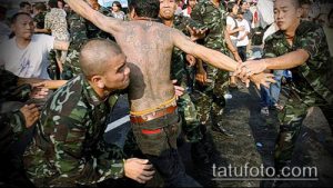 Фото: процесс нанесения сакральной татуировки сак янт тайским монахом, окруженным людьми, наблюдающими за ритуалом.