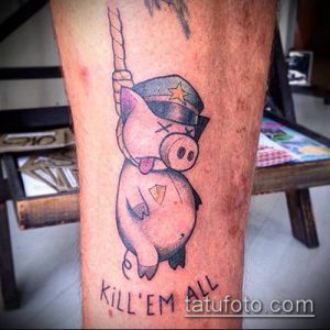 Фото тату поросенка в военной форме с повязкой на глазу и надписью 'Kill 'Em All'. Рисунок выполнен в черно-серых тонах, с добавлением красных акцентов.