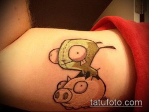 Яркое фото татуировки с изображением персонажей мультфильма Invader Zim и свиньи на плече. Рисунок выполнен в мультяшном стиле с использованием ярких цветов.
